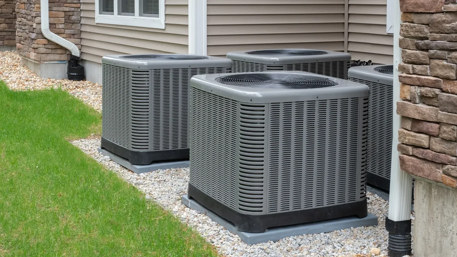 Outdoor condenser units with top-mounted fans beside a house